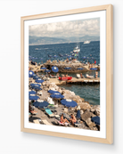 Santa Margherita fine-art print by Sam Smeaton — Mediterranean harbour and blue umbrellas, framed in natural oak for warm coastal texture.