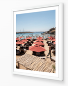 Paros Beach Club fine-art print in white frame by Sam Smeaton — Aegean coastal wall art with terracotta umbrellas and blue sea