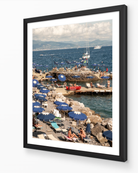 Santa Margherita fine-art print by Sam Smeaton — blue umbrellas and sea, framed in classic black frame for bold coastal contrast