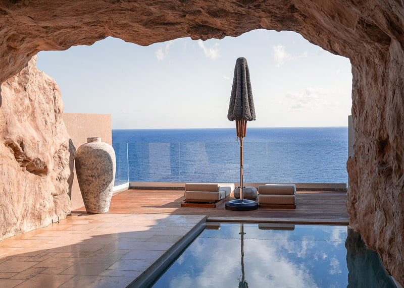 Luxury infinity pool carved into rock with sea view and minimalist design.