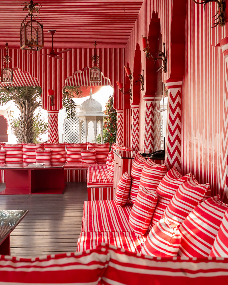 Outdoor striped veranda with red-and-white seating and arches at Villa Palladio Jaipur — editorial hotel photography by Sam Smeaton.