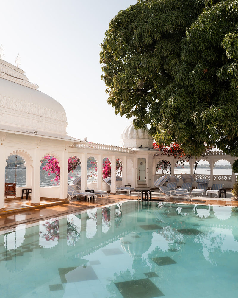 Pool terrace at Taj Lake Palace Udaipur framed by white marble arches, pink bougainvillea, and lake reflections — luxury hotel photography by Sam Smeaton.