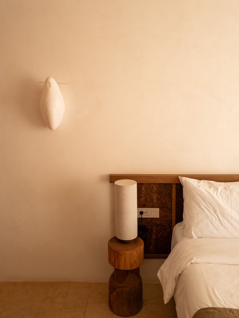 Minimalist bedroom with textured plaster walls and soft light, Greek island design.