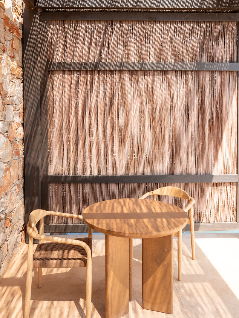 Outdoor terrace dining with timber chairs and shadow patterns in natural light.