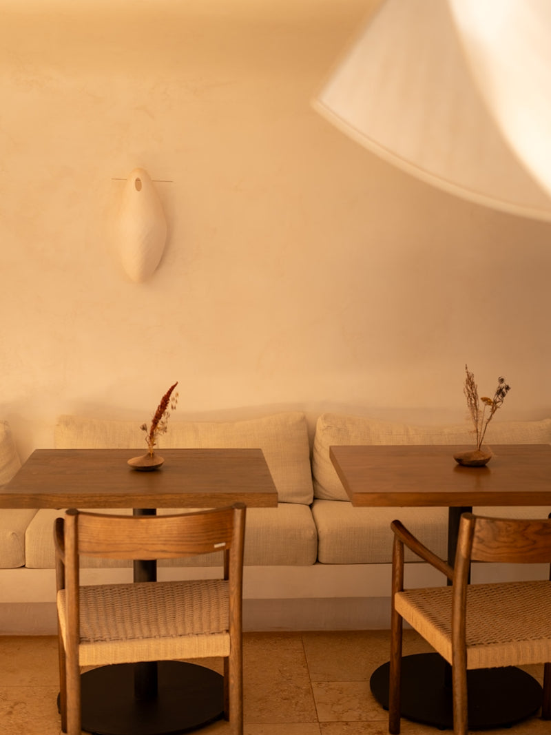 Small Mediterranean café with wooden tables, linen seating, and warm natural tones.