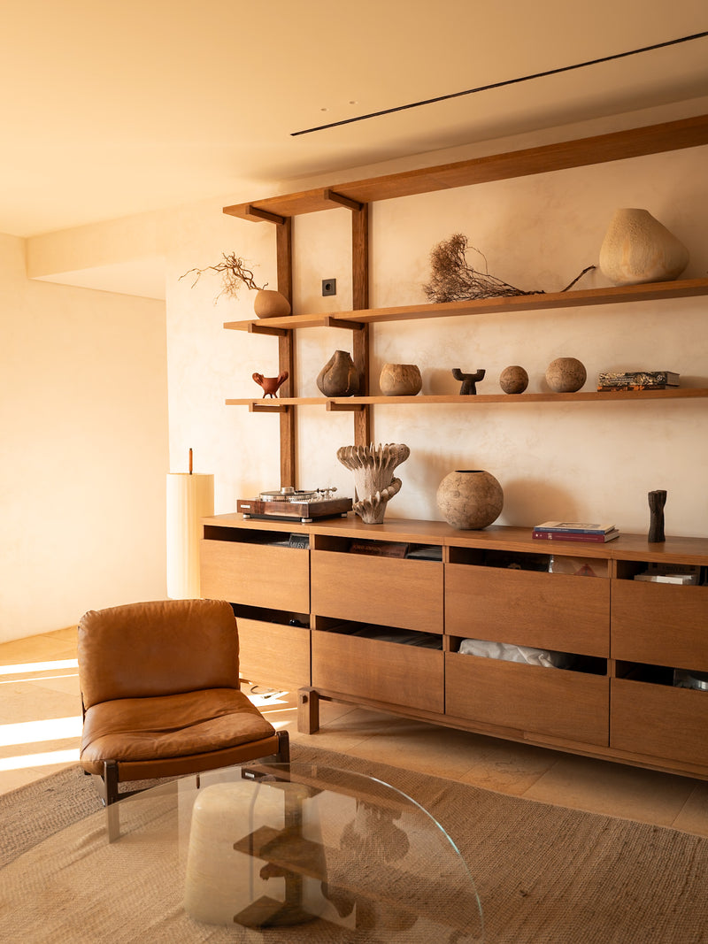 Editorial hotel suite interior with leather chair and terrace view in warm tones.