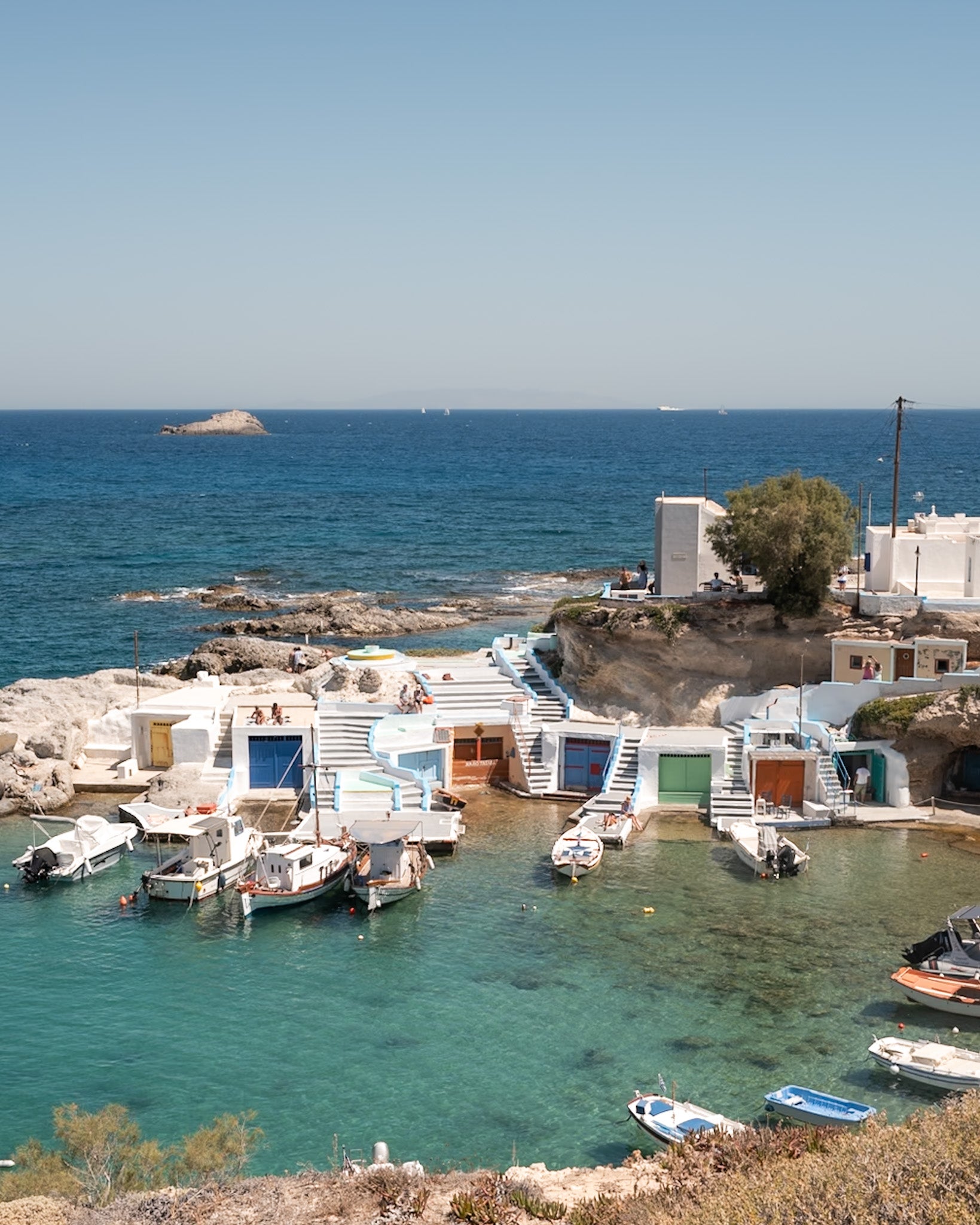 Mandrakia I – Milos fine-art print by Sam Smeaton — whitewashed Greek boathouses, turquoise water, and anchored boats in a calm Aegean cove