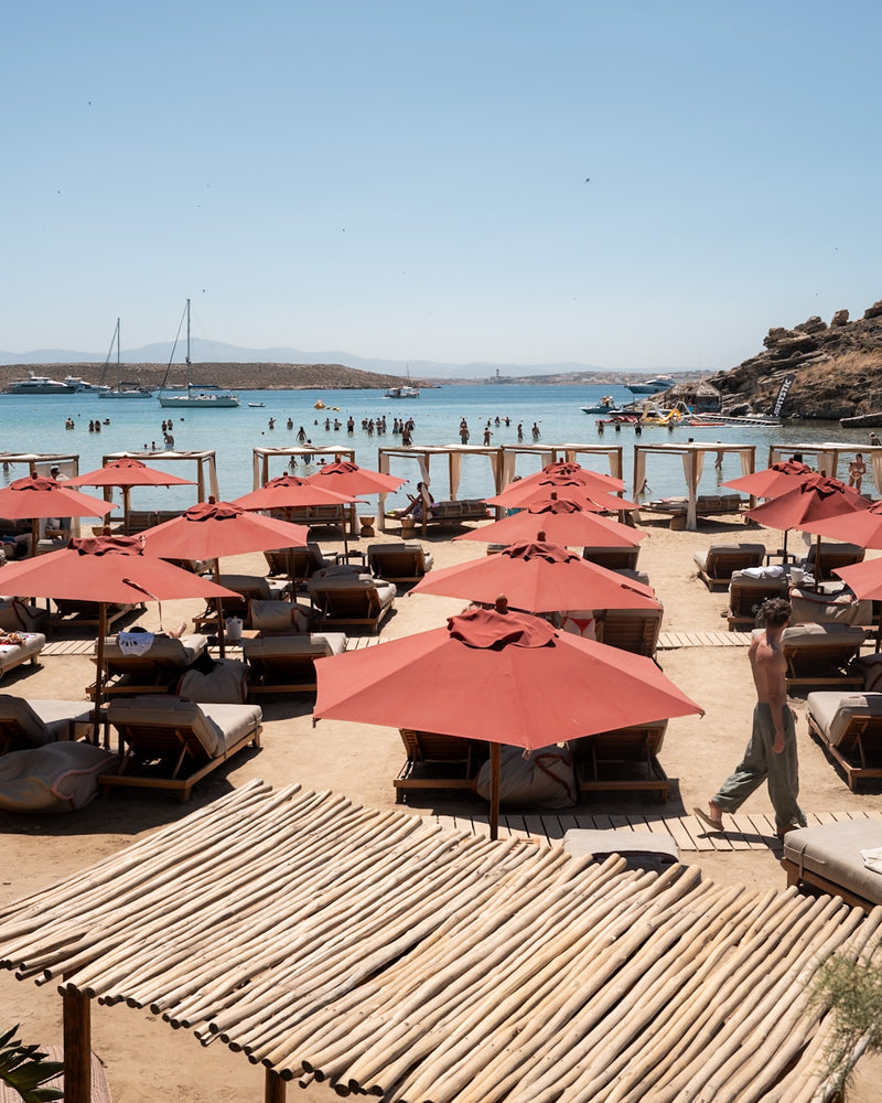 Seaside resort with red umbrellas and loungers, editorial hotel photography in Greece.