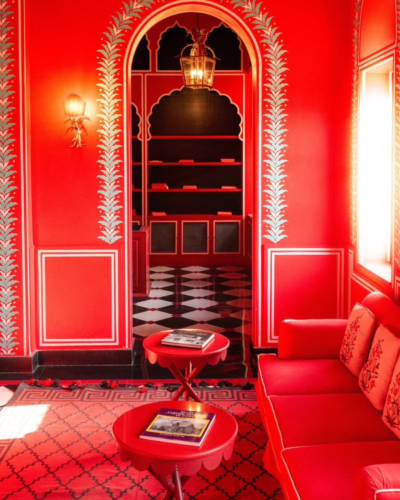 Red lounge interior with patterned archways and black-and-white tiled floor at Villa Palladio Jaipur — photographed by Sam Smeaton, boutique hotel photographer.