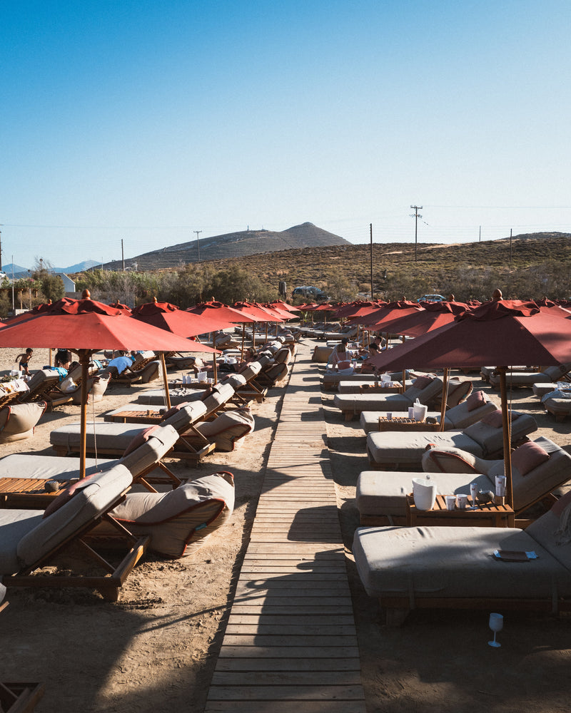Seaside deck with red umbrellas and loungers, photographed for luxury hotel brand.