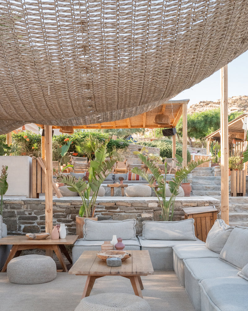 Open-air restaurant under rattan canopy with natural furnishings and greenery.
