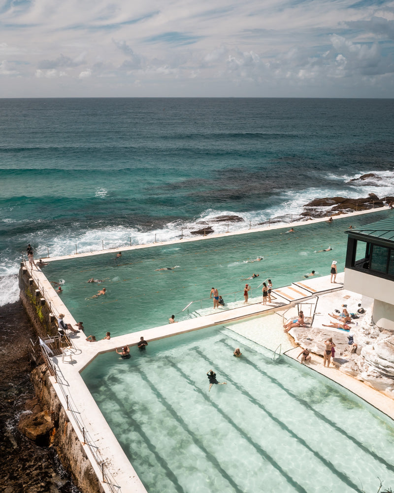 Sydney Icebergs – Bondi Pool fine-art print by Sam Smeaton — vertical aerial view of Bondi’s turquoise ocean pool beside the Pacific with white architecture and calm waves