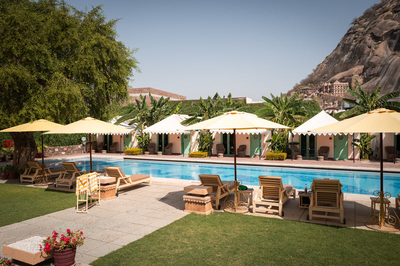 Poolside cabanas and yellow umbrellas at a heritage retreat in Ranthambore, Rajasthan — boutique resort photography by Sam Smeaton.