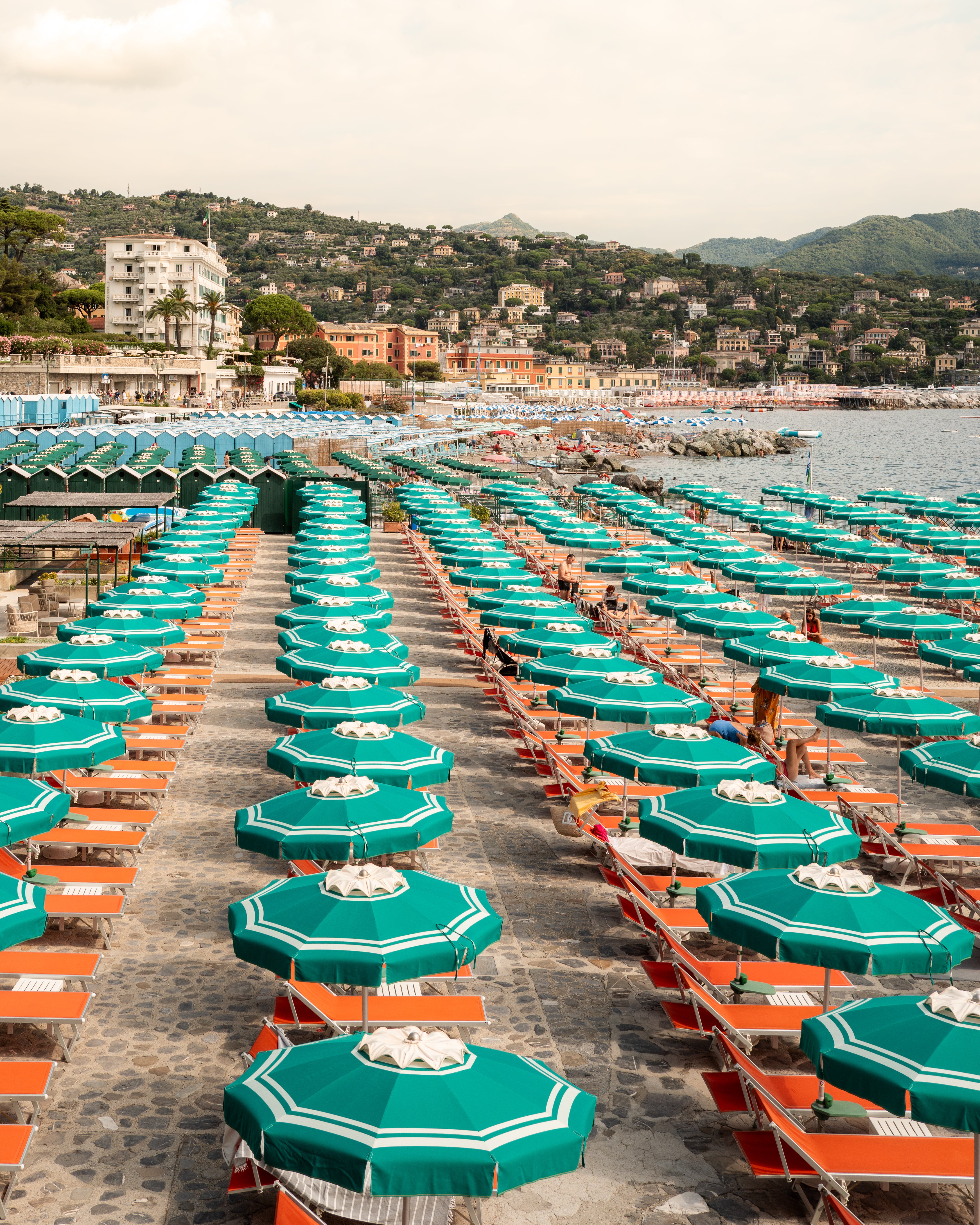 Fine-art photography print of Portofino Beach Club (Vertical Edition) by Sam Smeaton — turquoise umbrellas and orange sunbeds along the Italian Riviera, printed on premium matte fine-art paper, 50 × 75 cm.