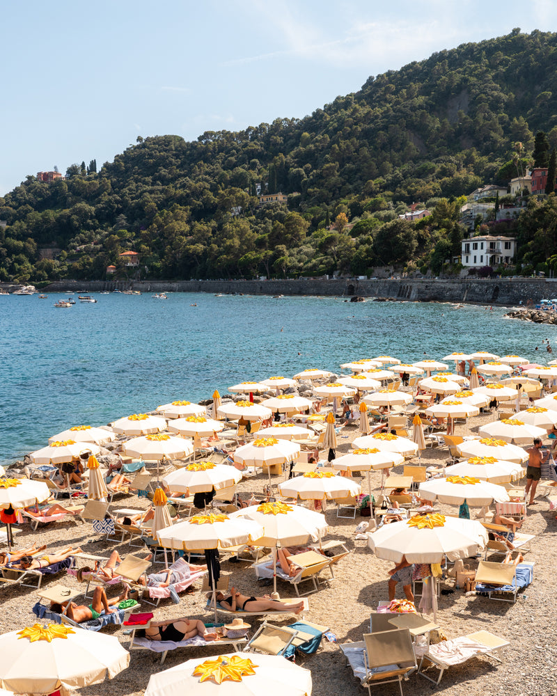 Fine-art photography print of Santa Margherita by Sam Smeaton — golden umbrellas on the Italian Riviera beneath green hills and turquoise water, captured in warm summer light, printed on matte fine-art paper, 50×75 cm.
