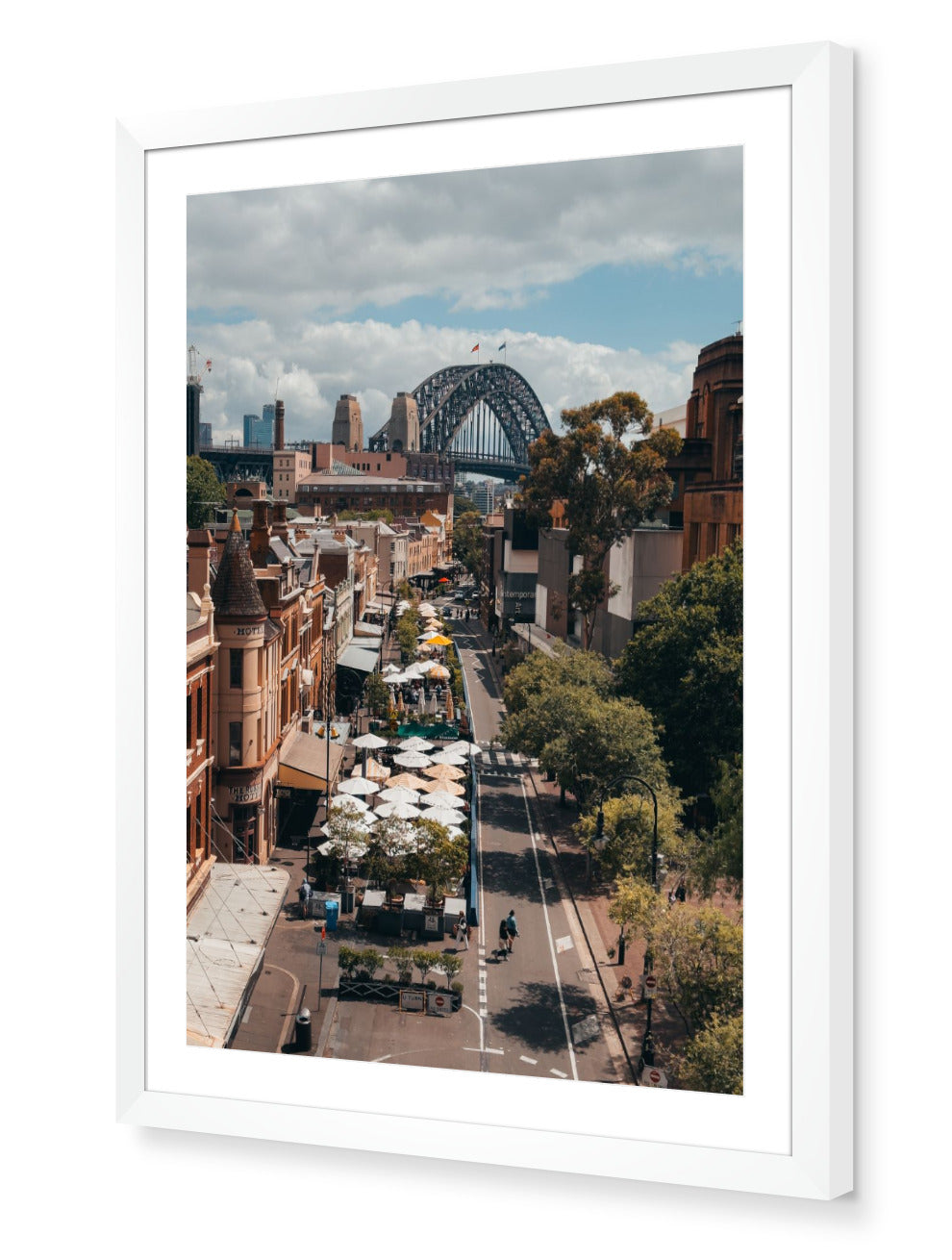 The Rocks – Sydney Harbour Bridge fine-art print in white frame by Sam Smeaton — view over Sydney’s historic The Rocks precinct with city skyline and Harbour Bridge in golden light